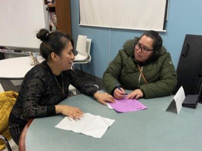 Two women sitting at a round table reviewing pages