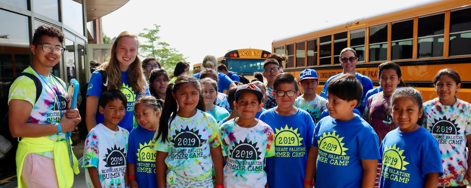 group photo of 2019 ICompete Summer Camp participants with school buses in the background